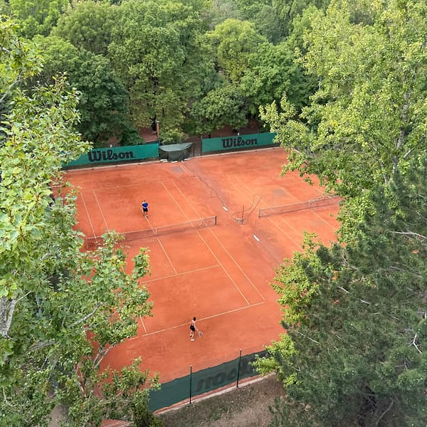 Dva antukové dvorce klubu TennisOne medzi stromami z výšky