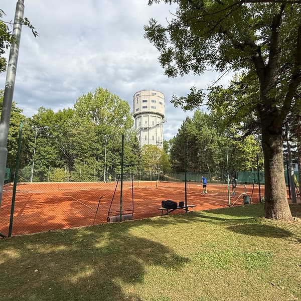 Antukový dvorec klubu TennisOne medzi stromami a osvetlením
