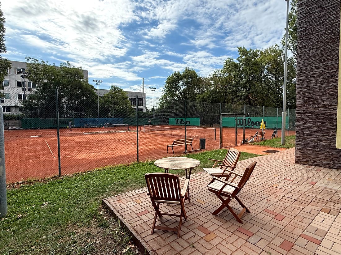Posedenie so stolom a stoličkami s výhľadom na dvorce klubu TennisOne